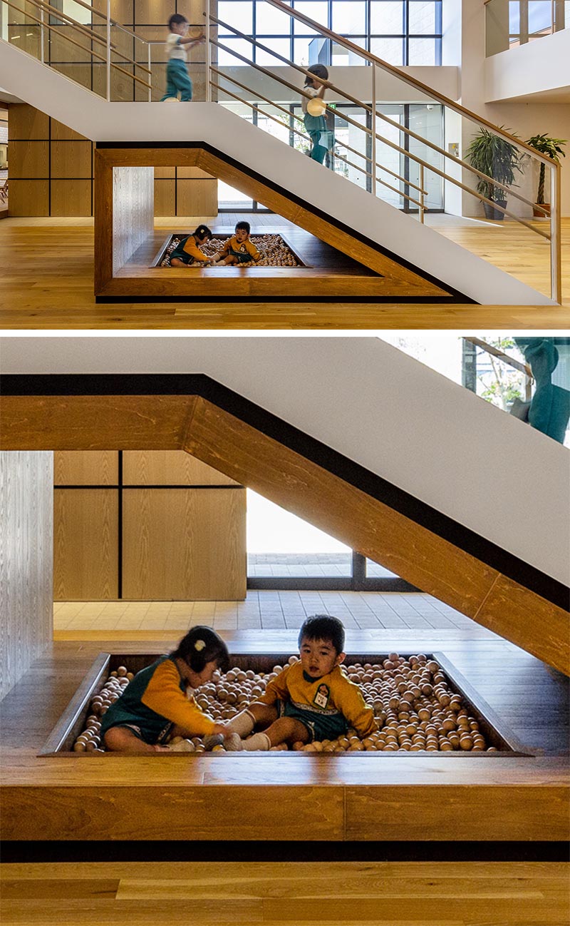 Located underneath the lower half of these kindergarten stairs is a wood framed area that's home to kids play area with a small ball pit. #KidsPlayArea #UnderStairDesign #KidsBallPit #InteriorDesign