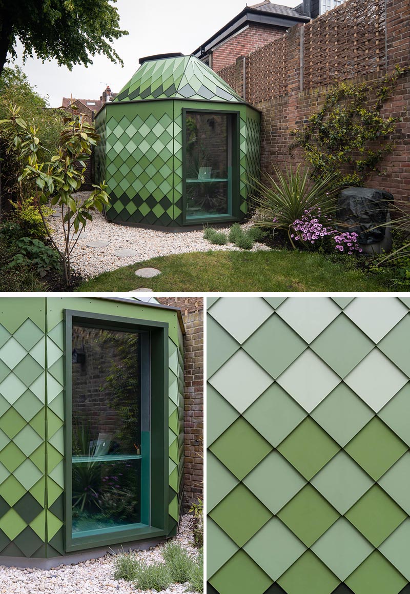 A backyard home office and guest suite that has a geometric shape and is covered in green shingles.