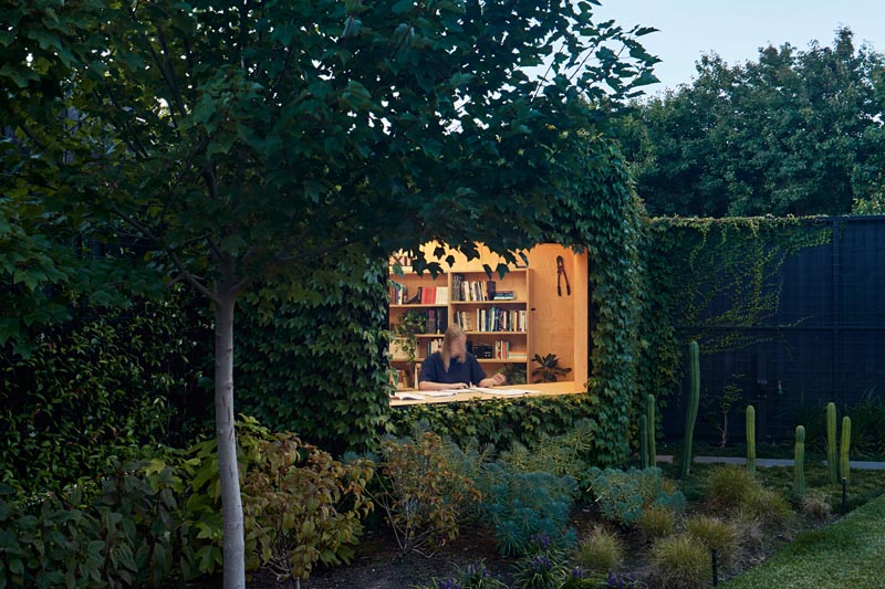 A small backyard home office is covered in Boston ivy.