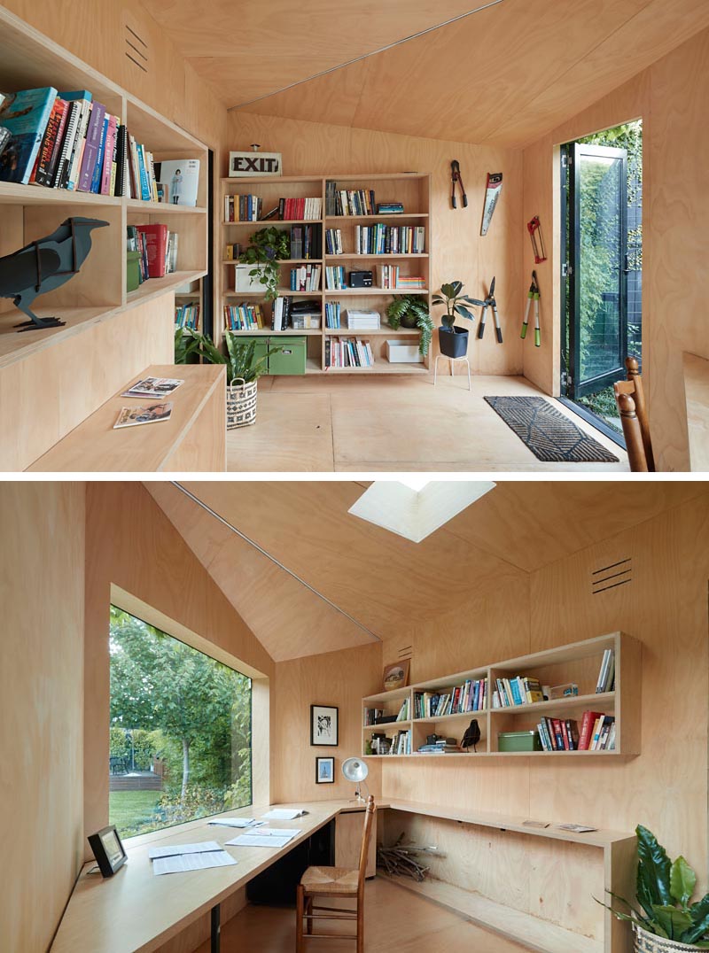 A small backyard home office has plywood walls, shelving, and a large desk.