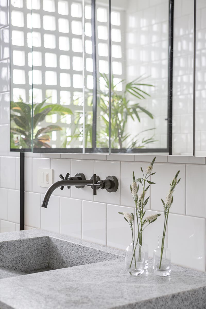 The natural wood vanity in this modern bathroom is topped with a Brazilian grey and white granite named "Branco Sao Paulo" in a matte finish, however it's the dual sinks with a sloped interior that are the focal point. #ModernBathroom #GraniteBathroomCountertop #GreyBathroom #ModernVanity