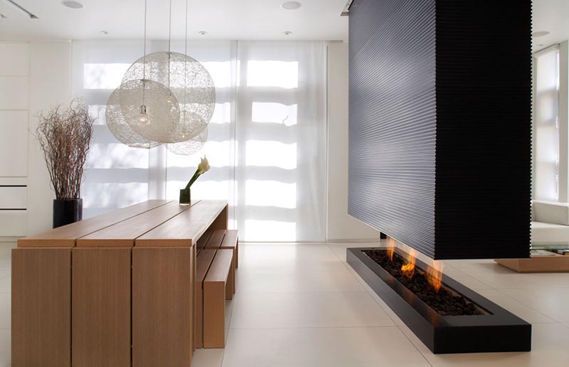 A black room divider separates the living room from the dining room, and includes a fireplace and a recessed television.