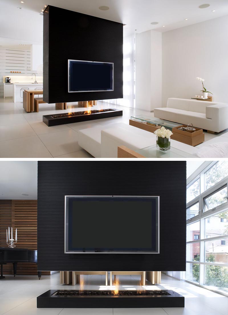 A black room divider has a recessed television and a see-through fireplace.