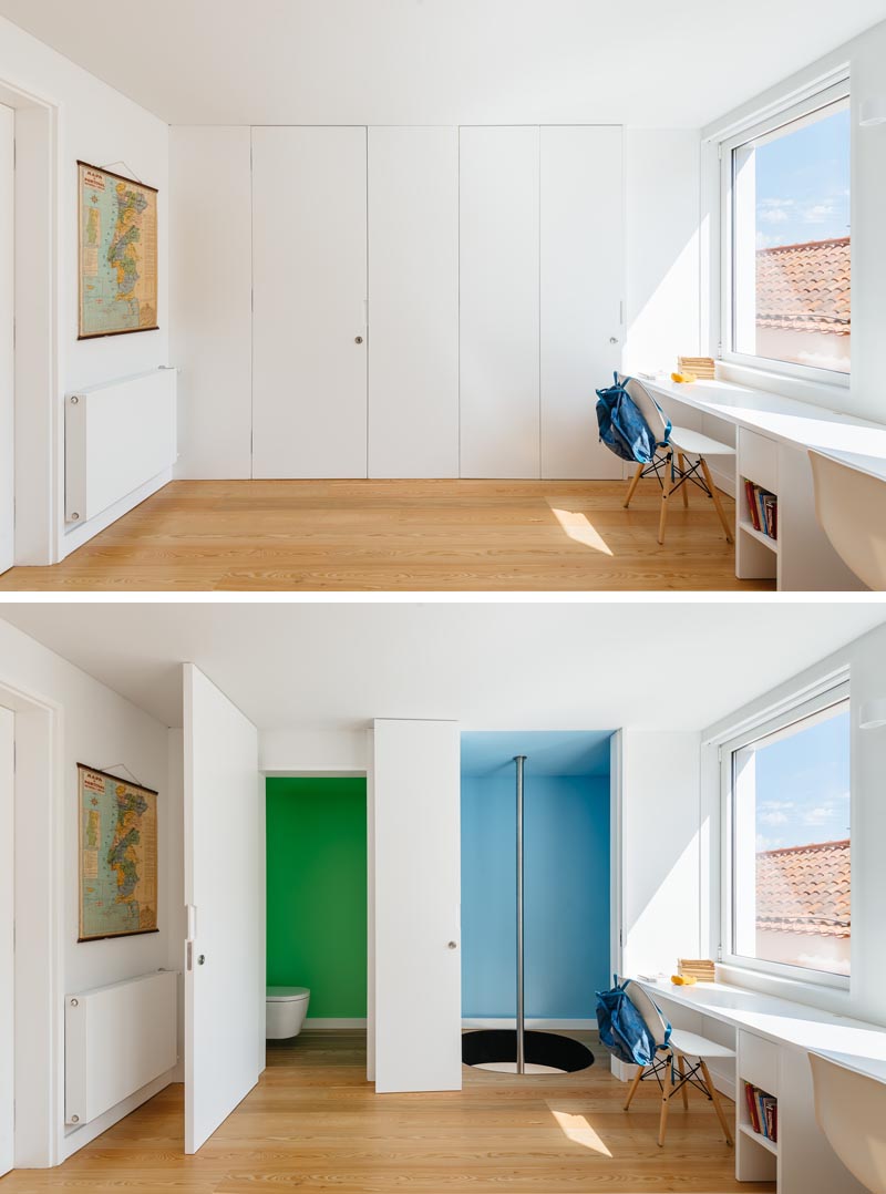 In the children's bedroom, two white doors are almost hidden within the wall. The first door opens to a bathroom with green walls, whereas the other door opens to reveal a mini blue room with a fire pole. #FirePole #KidsBedroom #FiremansPole #InteriorDesign