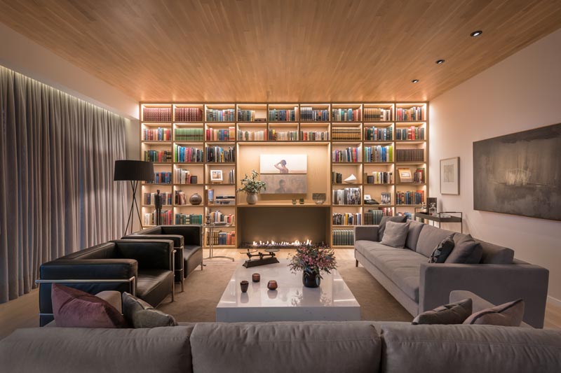 A living room wall full of shelving that has LED lighting to highlight the displayed decor and books.