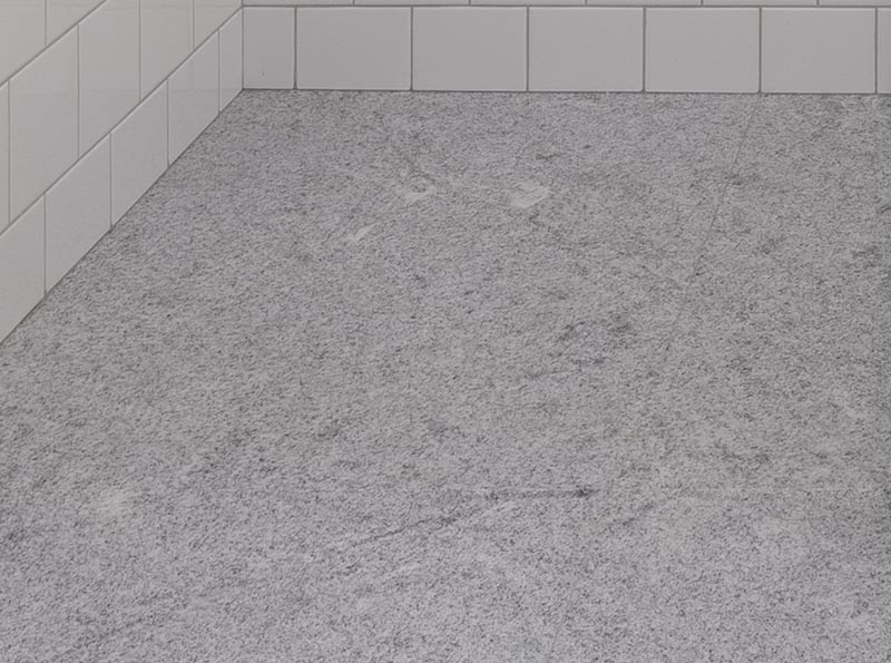 This modern bathroom features a Brazilian natural stone floor. By using a grey floor, it creates a neutral base for the white tiles, wood vanity, and black accents to stand out. #GraniteFloor #GraniteBathroomFloor #GreyFloor #NaturalStoneFloor