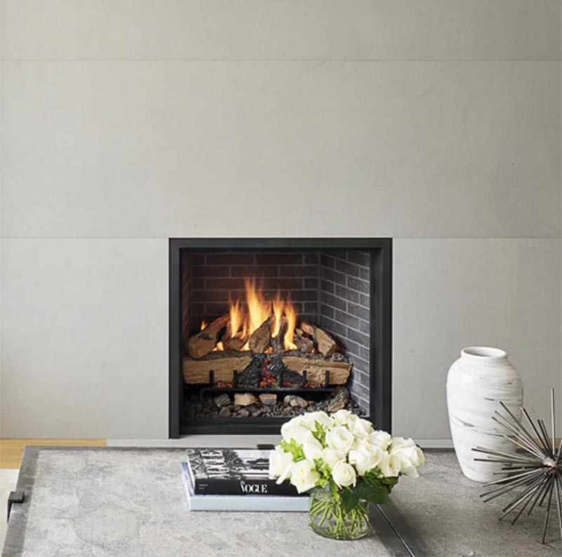 A grey fireplace surround, which travels from the floor to the ceiling,  contrasts the black frame and dark brick of the fireplace