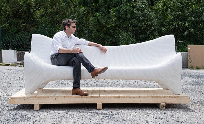 A white concrete outdoor couch made using 3D printing techniques.