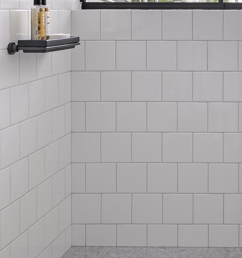 In this modern bathroom, floor-to-ceiling white tiles cover the walls, measure in at 15x15cm, have matching white grout. #SquareWhiteTiles #SquareTiles #BathroomIdeas