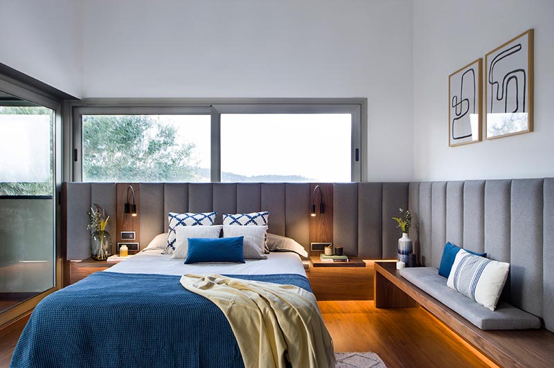 A modern master bedroom with an upholstered wraparound headboard.