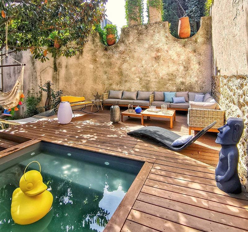 A backyard design that includes a raised lounge, a small pool, and hammocks.