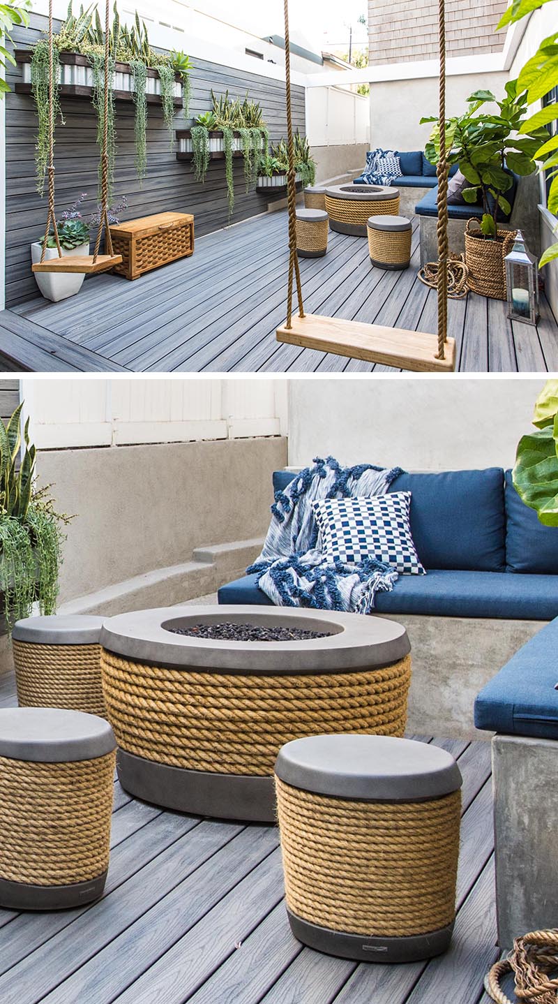 This modern side yard features a wood wall with planters, as well as a deck, both constructed of a Timber Tech material. In the corner, there's an L-shape bench with stools, a pair of swings, and a fire table made from concrete and rope. #SideYard #LandscapeDesign #ModernOutdoorSpace