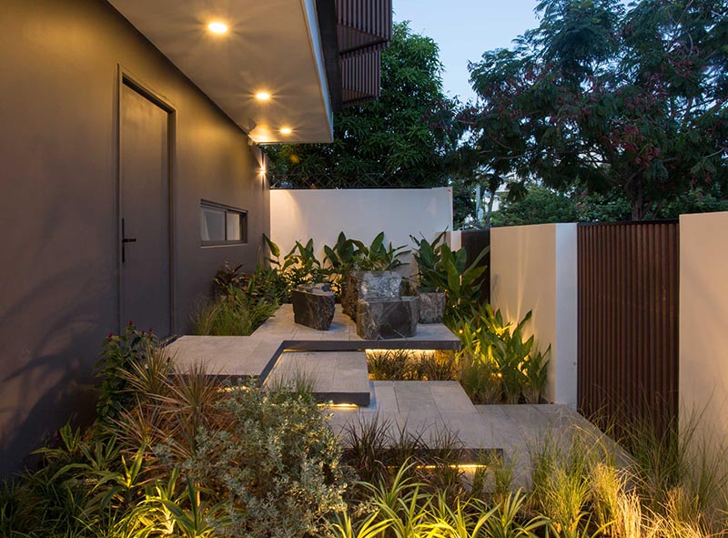 A small landscaped front garden includes overlapping steps, hidden lighting, and a small seating area.