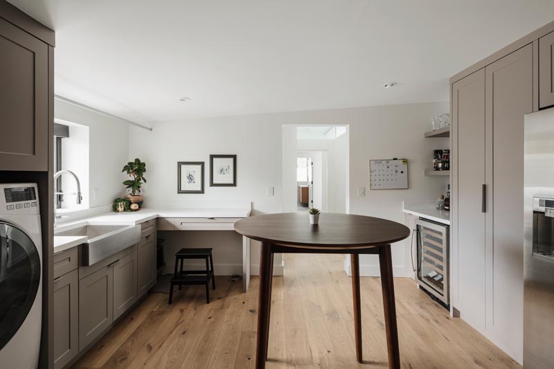 A modern pantry and laundry room that includes a bar, storage, farmhouse sink and washer/dryer.