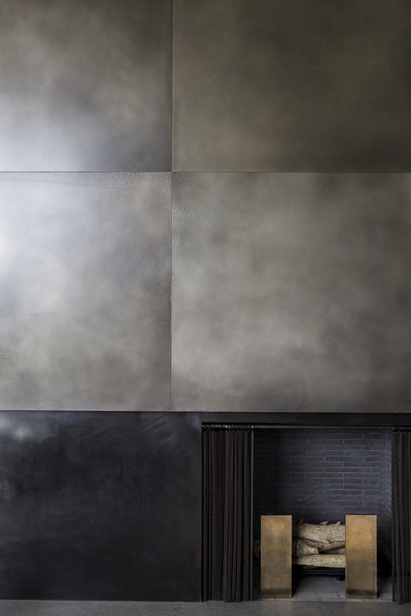 A metal fireplace surround made from brass panels in a silver nitrate finish.