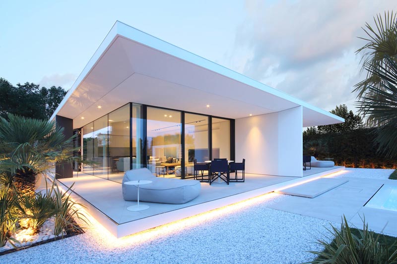 A minimalist white house with outdoor lighting that highlights the crisp architectural lines.