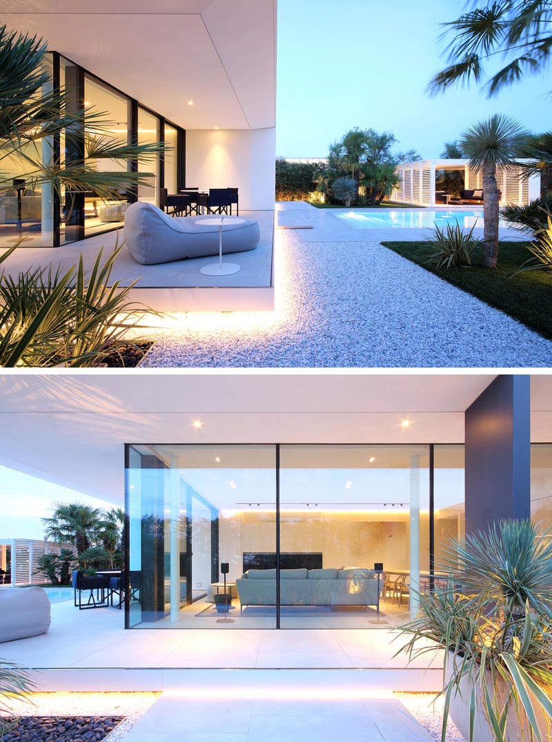 A minimalist white house with outdoor lighting that highlights the crisp architectural lines.