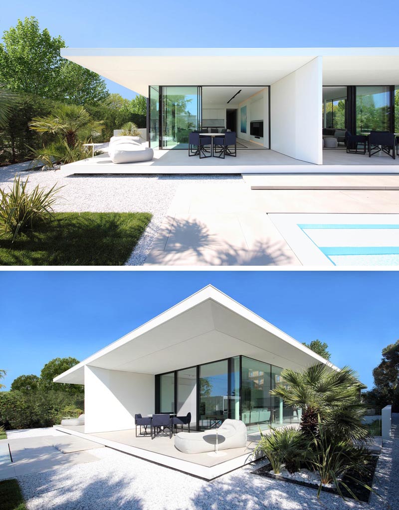 A minimalist white house with covered outdoor patios and glass walls.