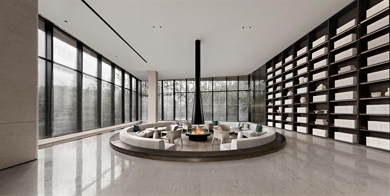 This sale center foyer a beige interior, however the sunken circular seating with its black border and fireplace create a contrast to the light color and complement the adjacent dark shelving. #ConversationPit #SunkenSeating #SunkenLounge