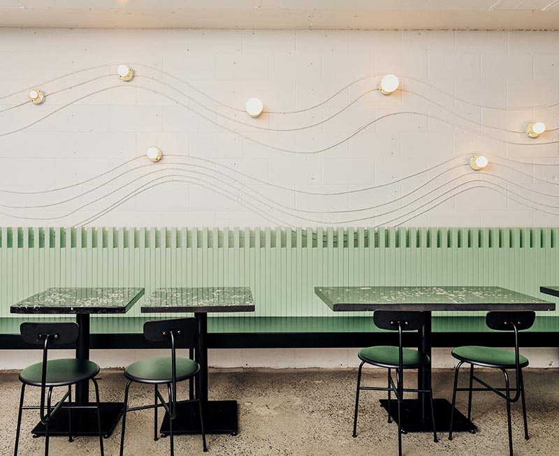 This modern restaurant design uses electrical conduit and keyless lamp fixtures to create attractive wall art that lightly traces the shape of a wave.