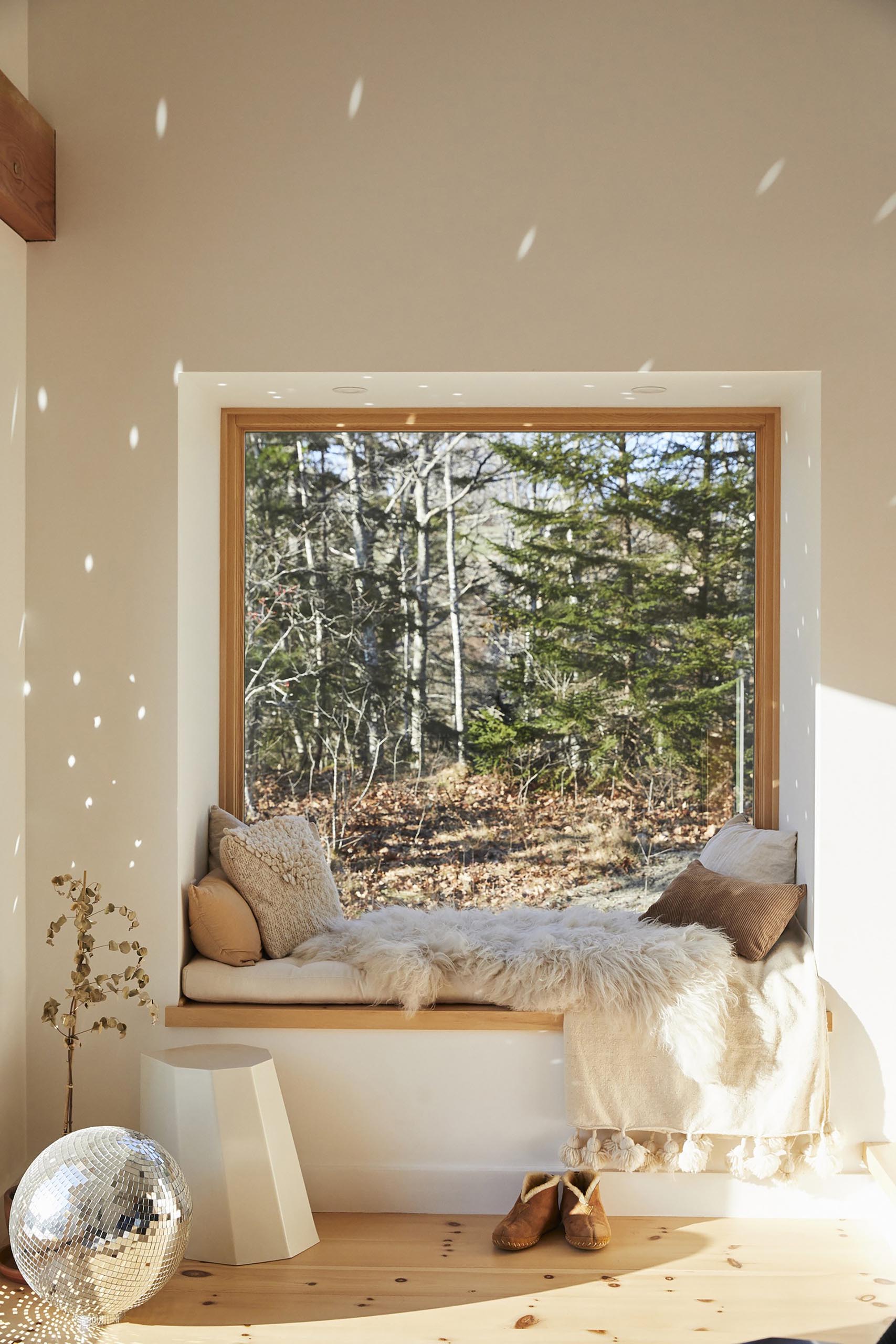 A cozy window seat with tree views, soft pillows and blankets, and a mirror ball that scatters light.