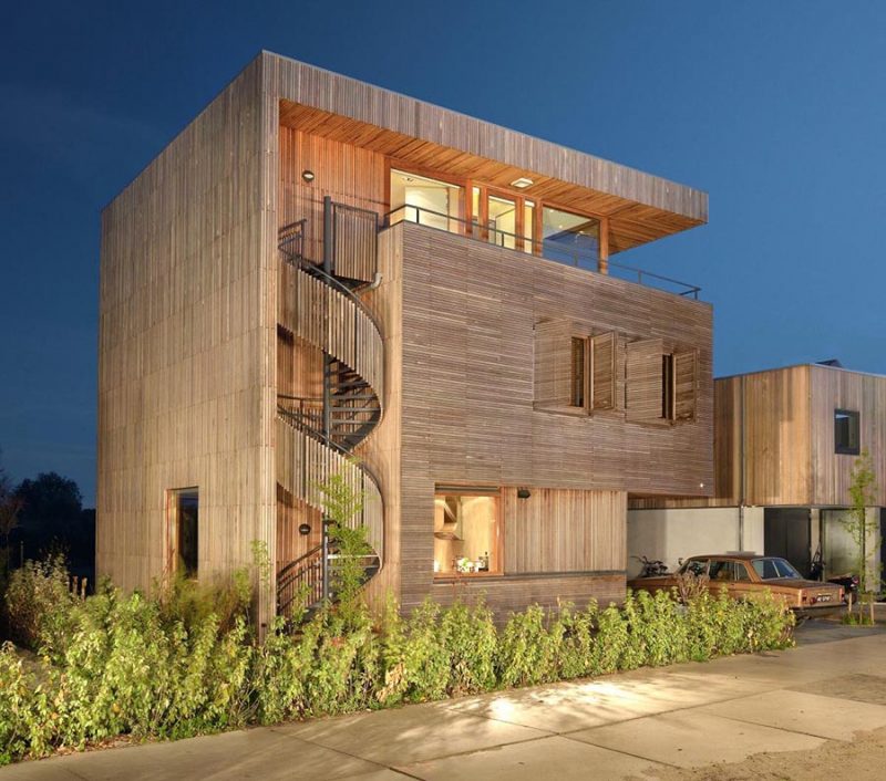 A modern wood house with an exterior spiral staircase covered in wood slats.