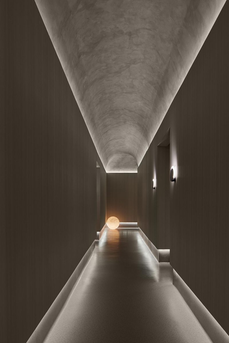 Indirect lighting showcases the curved ceiling and flooring in this hallway.