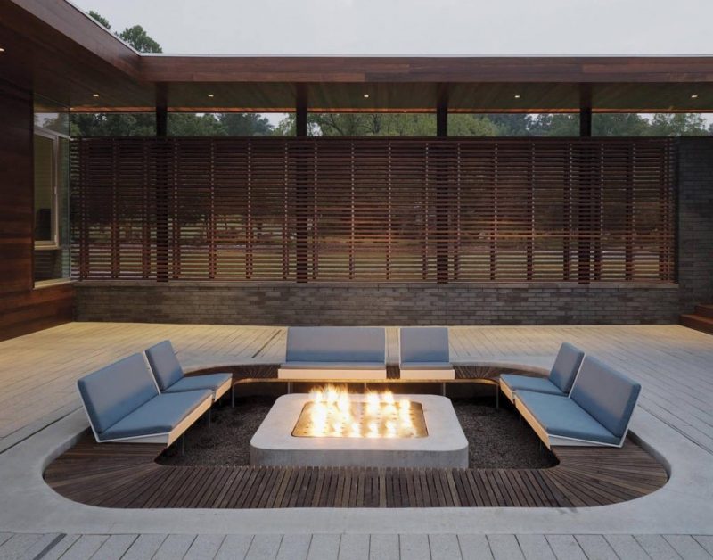 A modern outdoor conversation pit with a square shape and custom seating that's focused on the fire.