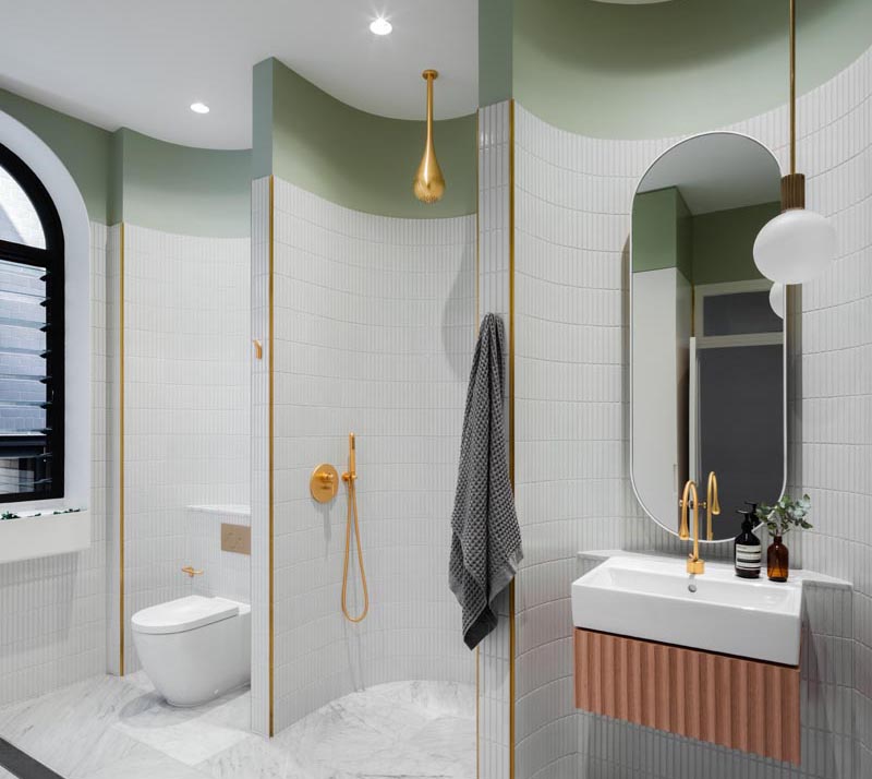 Curved walls in this modern bathroom divide the space into areas for a vanity, the shower, and the toilet.