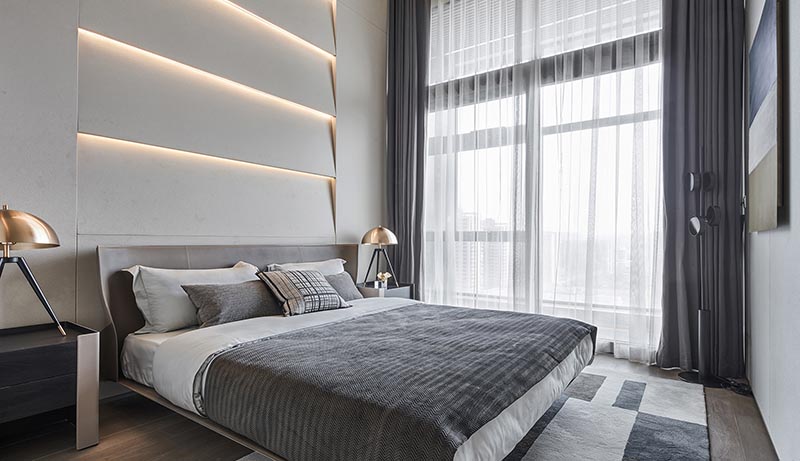A modern bedroom with an accent wall made from multi-layered sections and hidden lighting