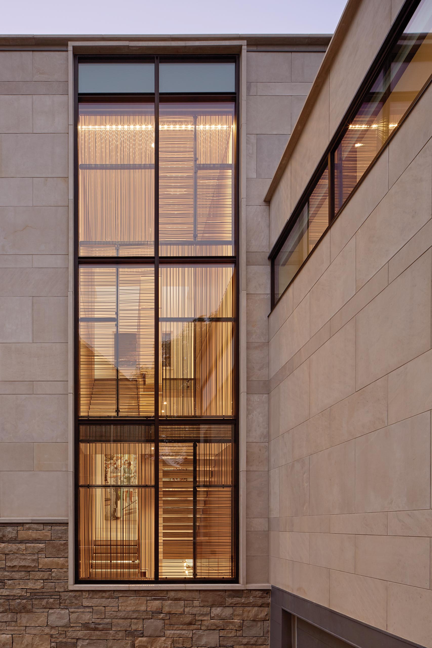 A modern house with Indiana Limestone, split faced Ontario Algonquin stone, and bronze privacy screens.