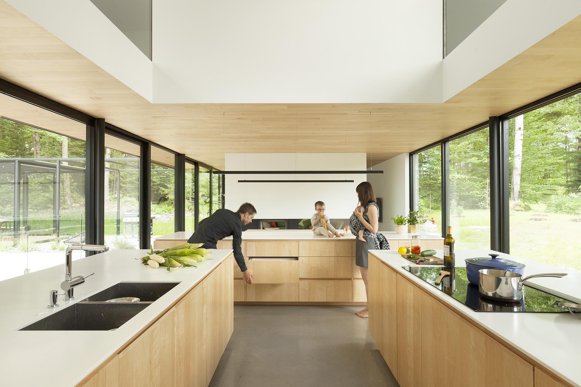 A modern kitchen design with three islands, a double height ceiling, and a wall of cabinets.