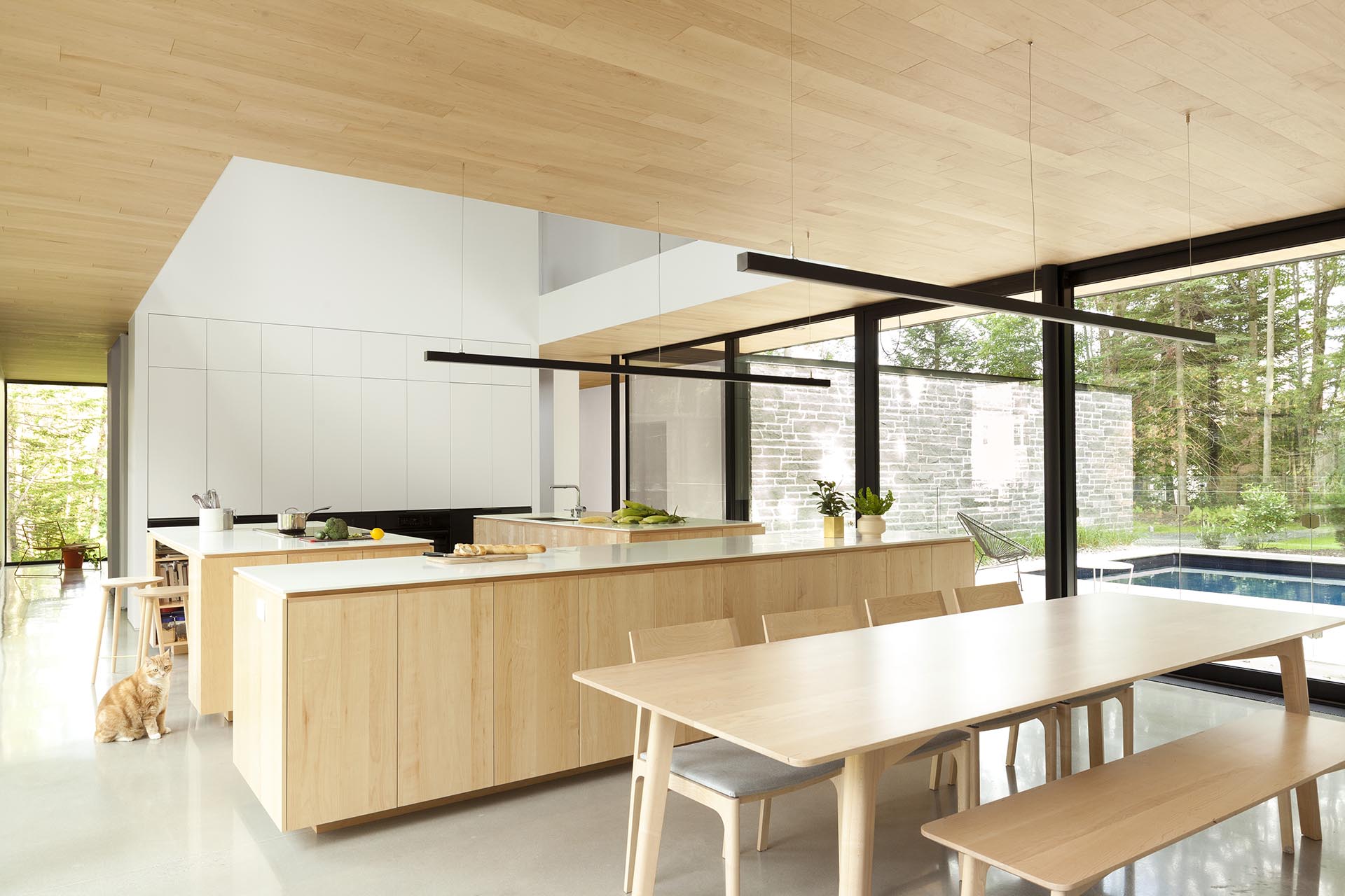 A modern kitchen with three kitchen islands with a light wood base and white countertops.