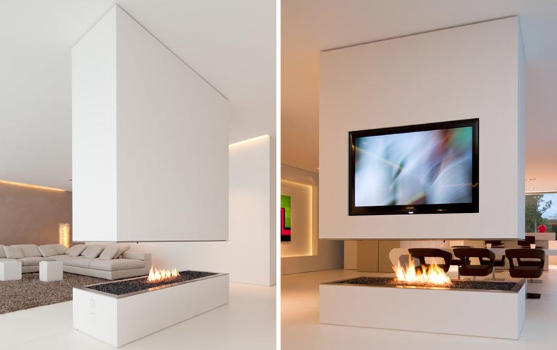 A minimalist white room divider with a fireplace and a recessed television.