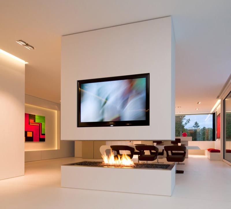 A white room divider with a recessed television and an open gas fireplace.