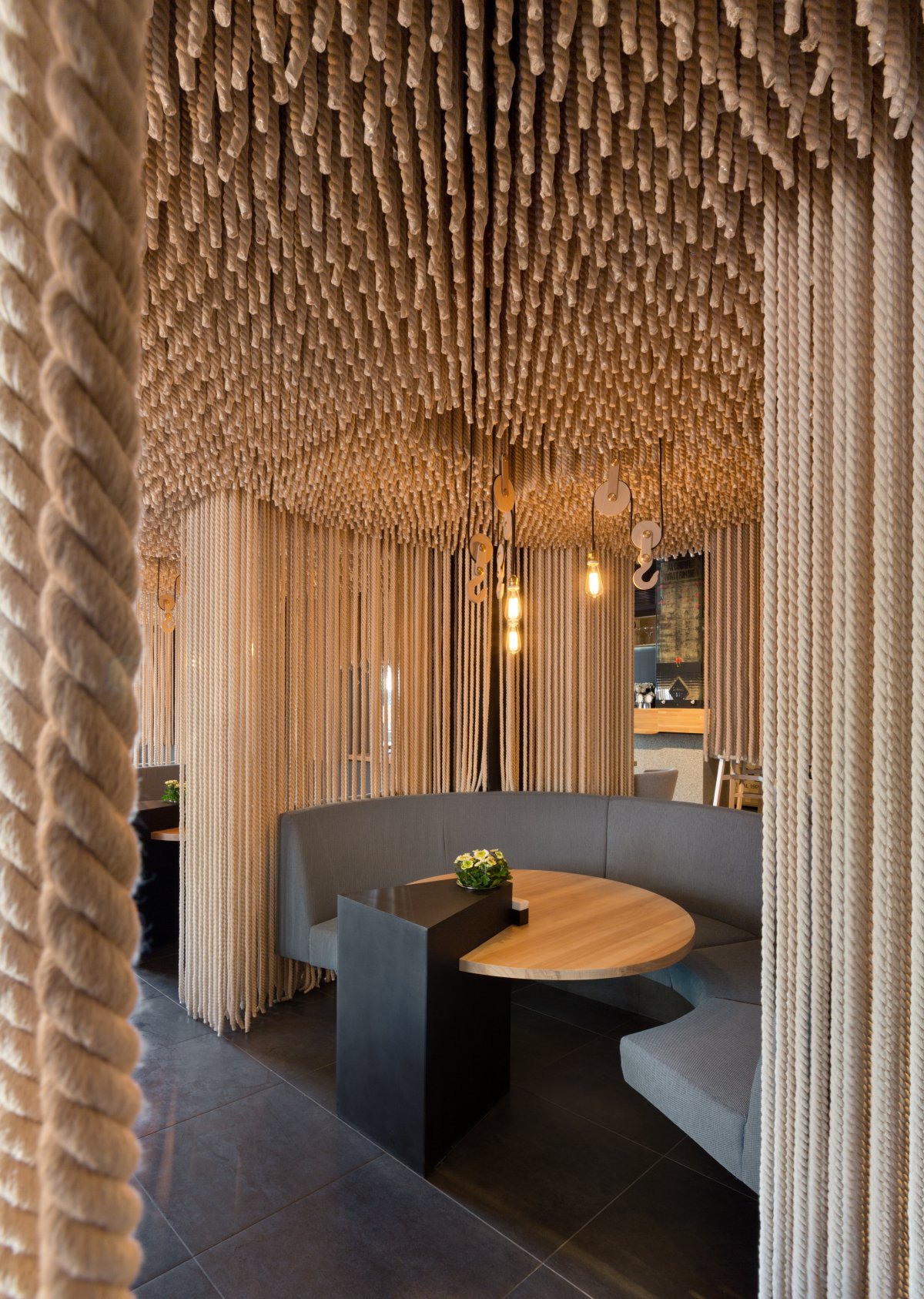 A modern restaurant with rope room dividers and ceiling installation.