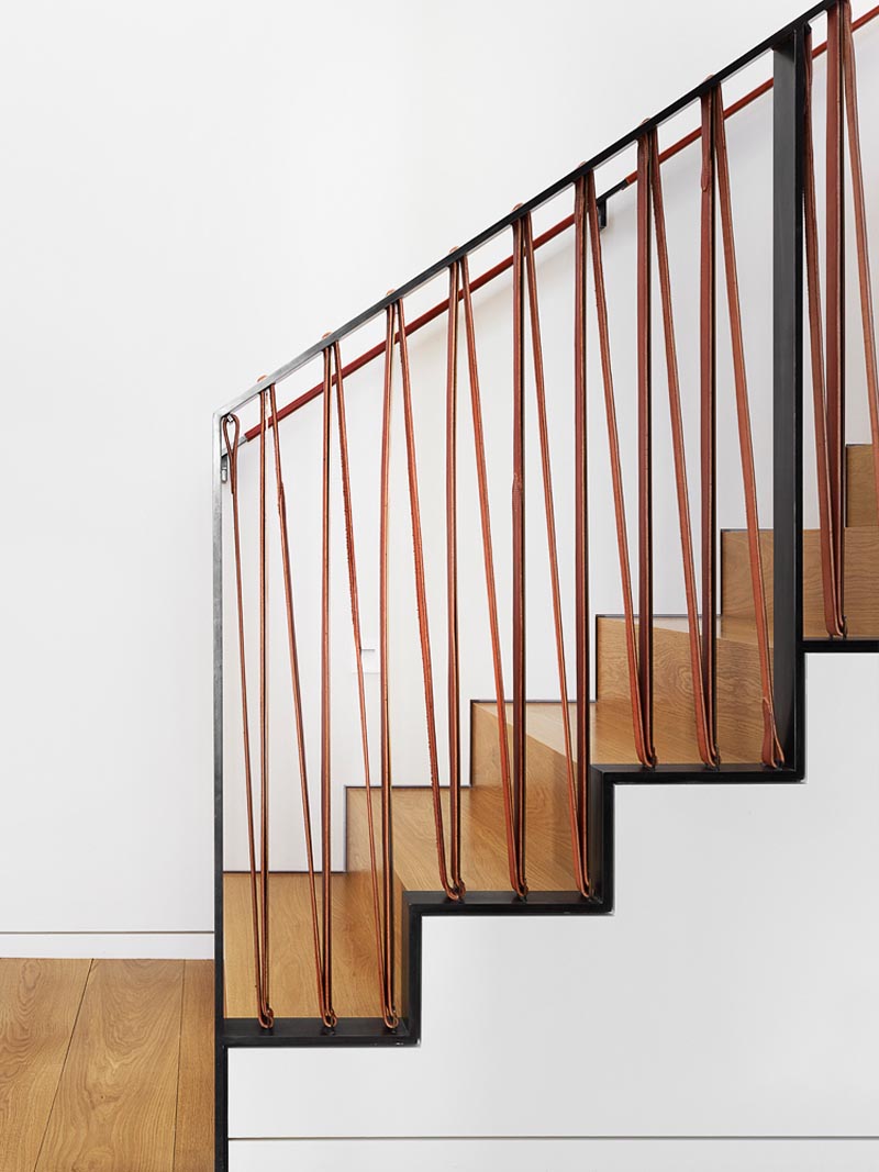 A stair railing made from black steel and soft saddle leather.