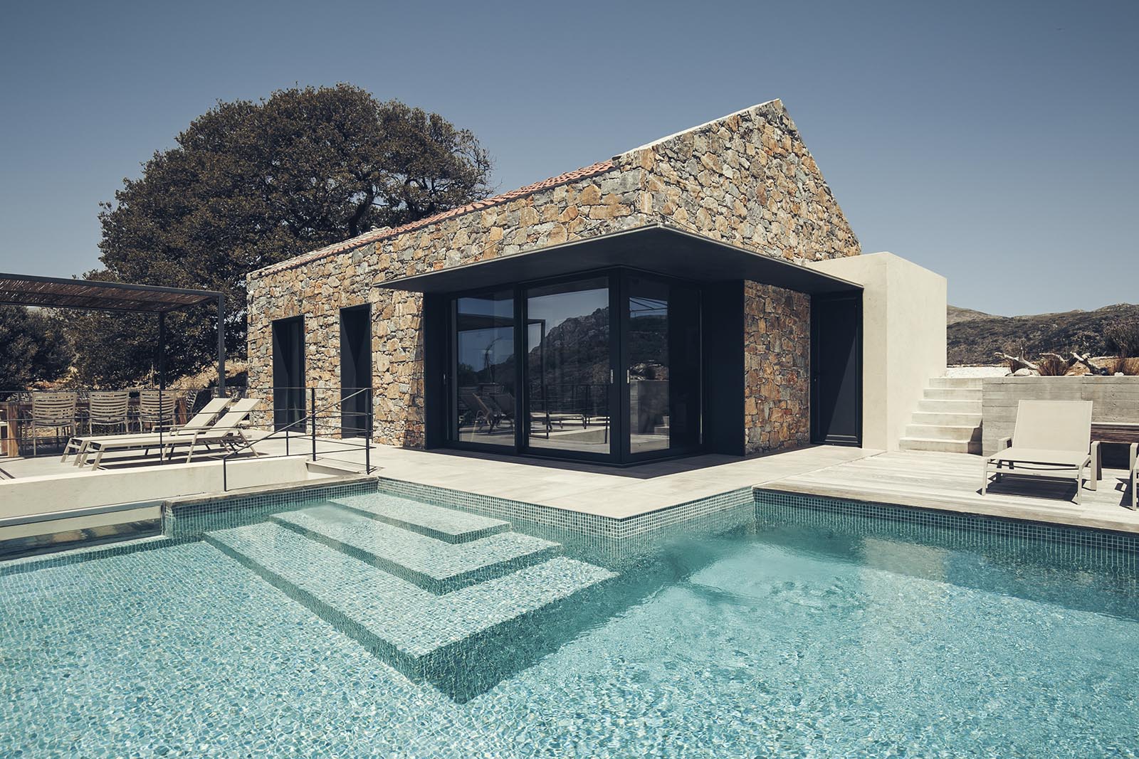 A summer house with black metal accents that contrast the stone walls.