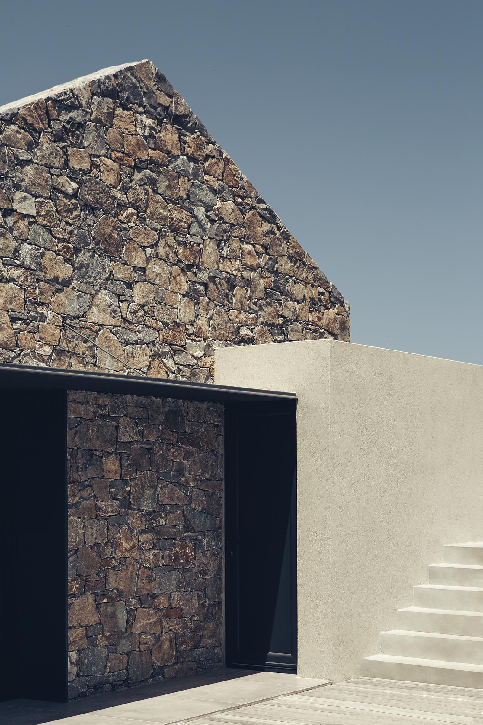 Black metal accents contrast the stonework of this contemporary house.