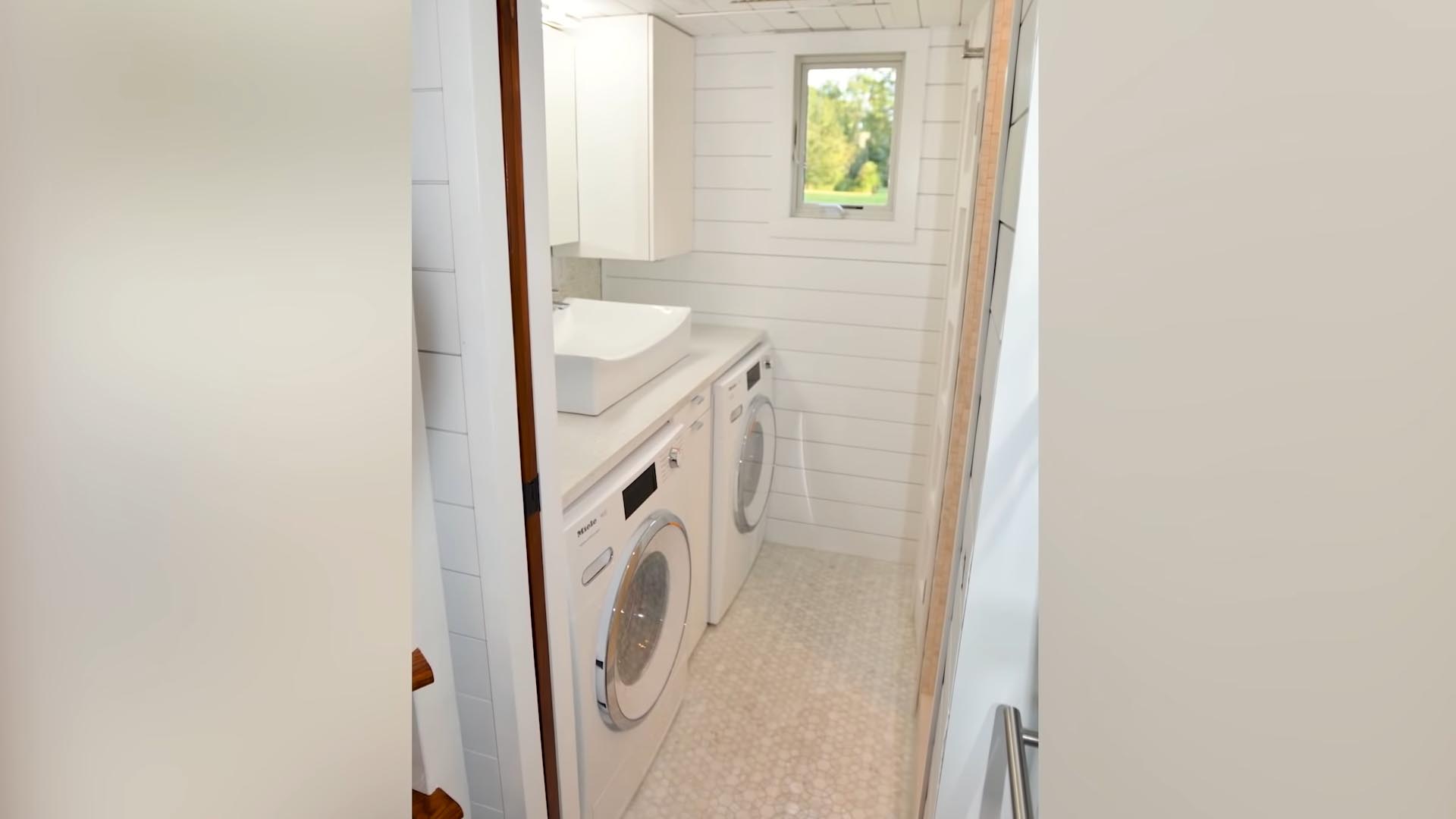 A tiny house bathroom with washer/dryer, and walk-in shower.