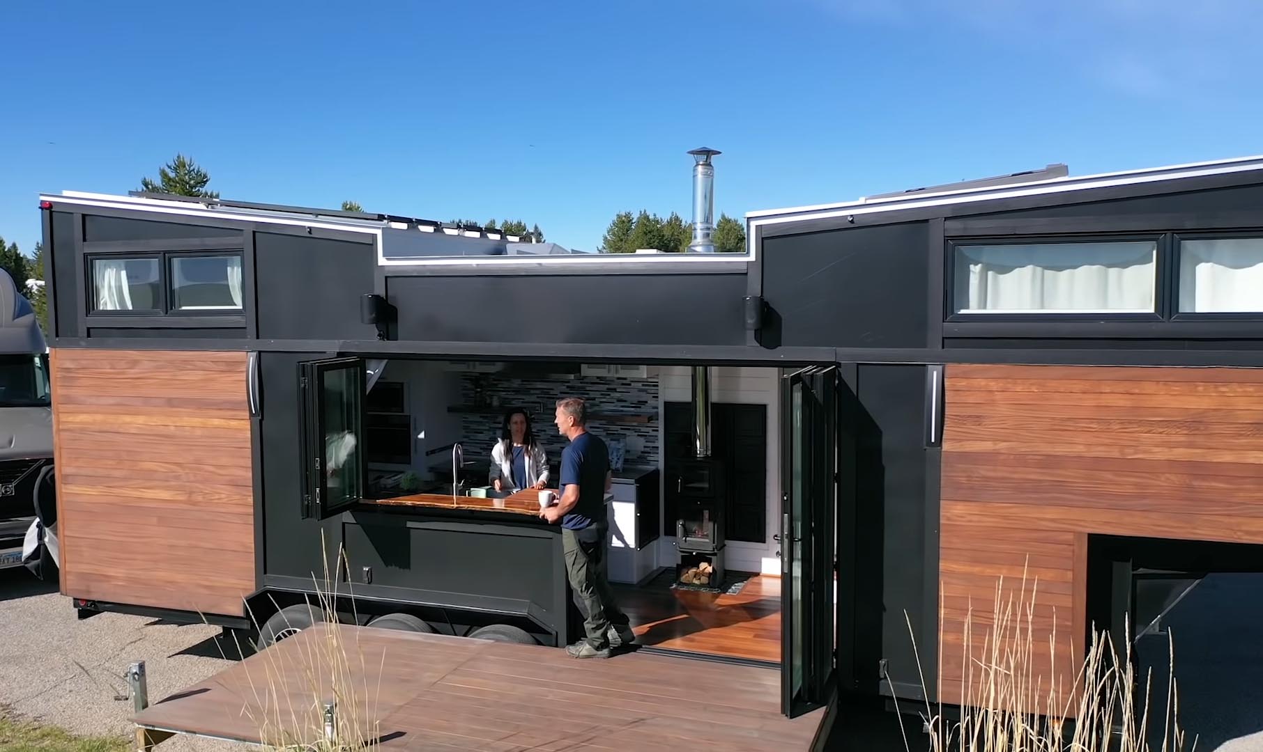 A high-end tiny house with wood siding and glass doors that open to a deck.