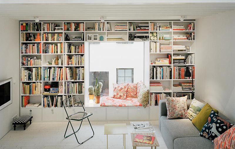 A cozy window seat surrounded by shelves.