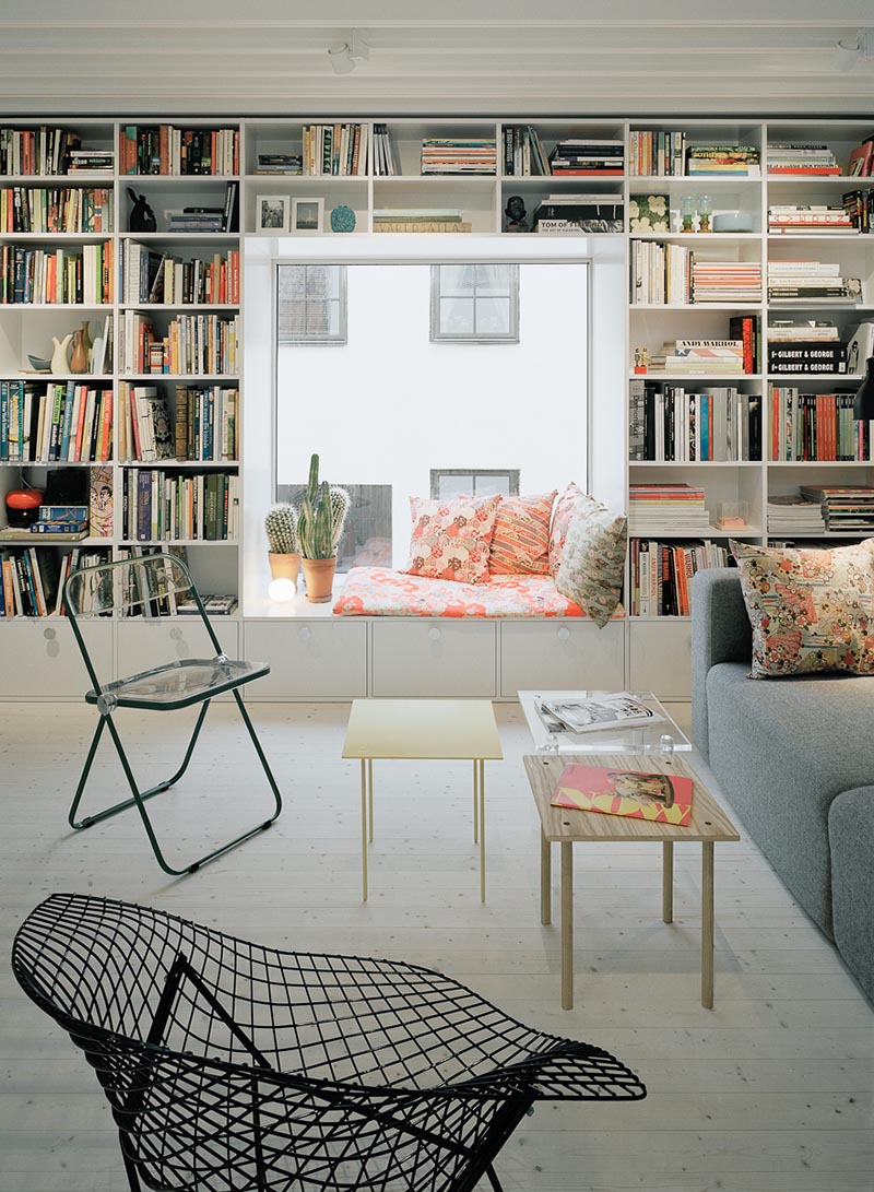 A cozy window seat surrounded by shelves.