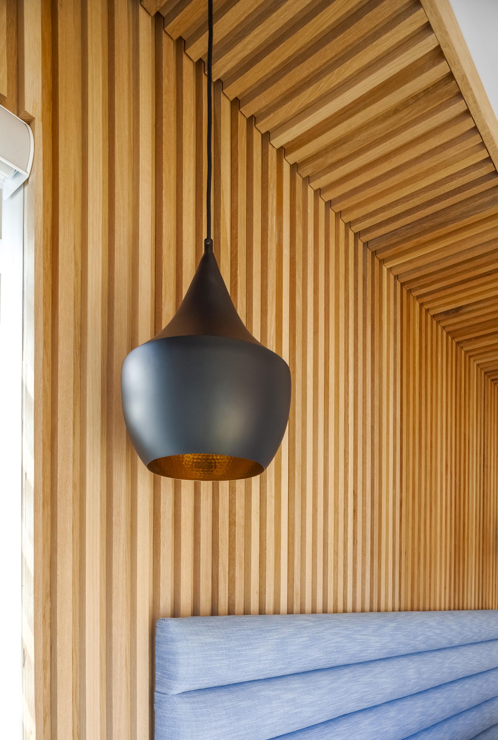 A wood accent wall with a modern black pendant light.