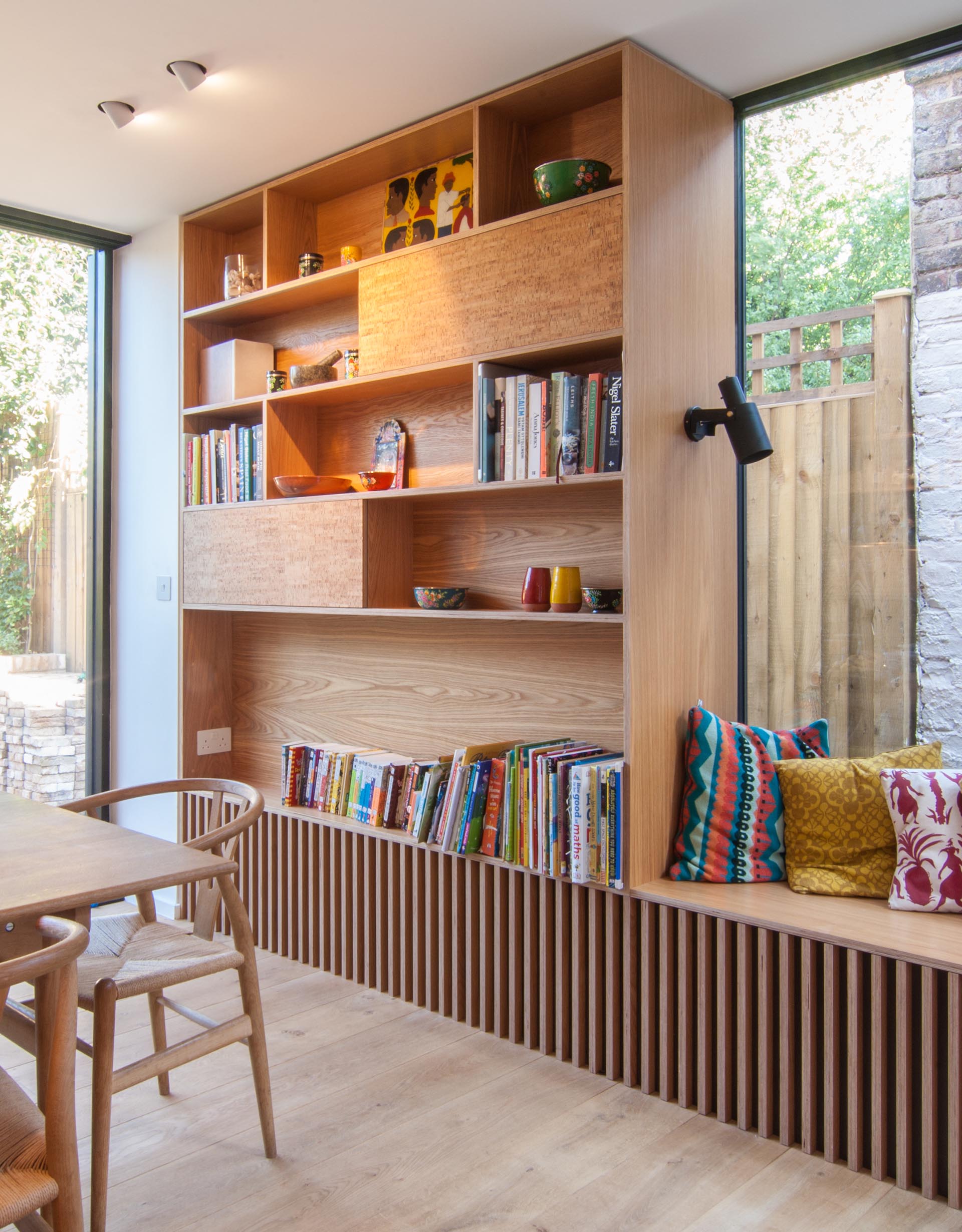 A tall bookshelf next to a window bench provides a place to display decor and a book collection.