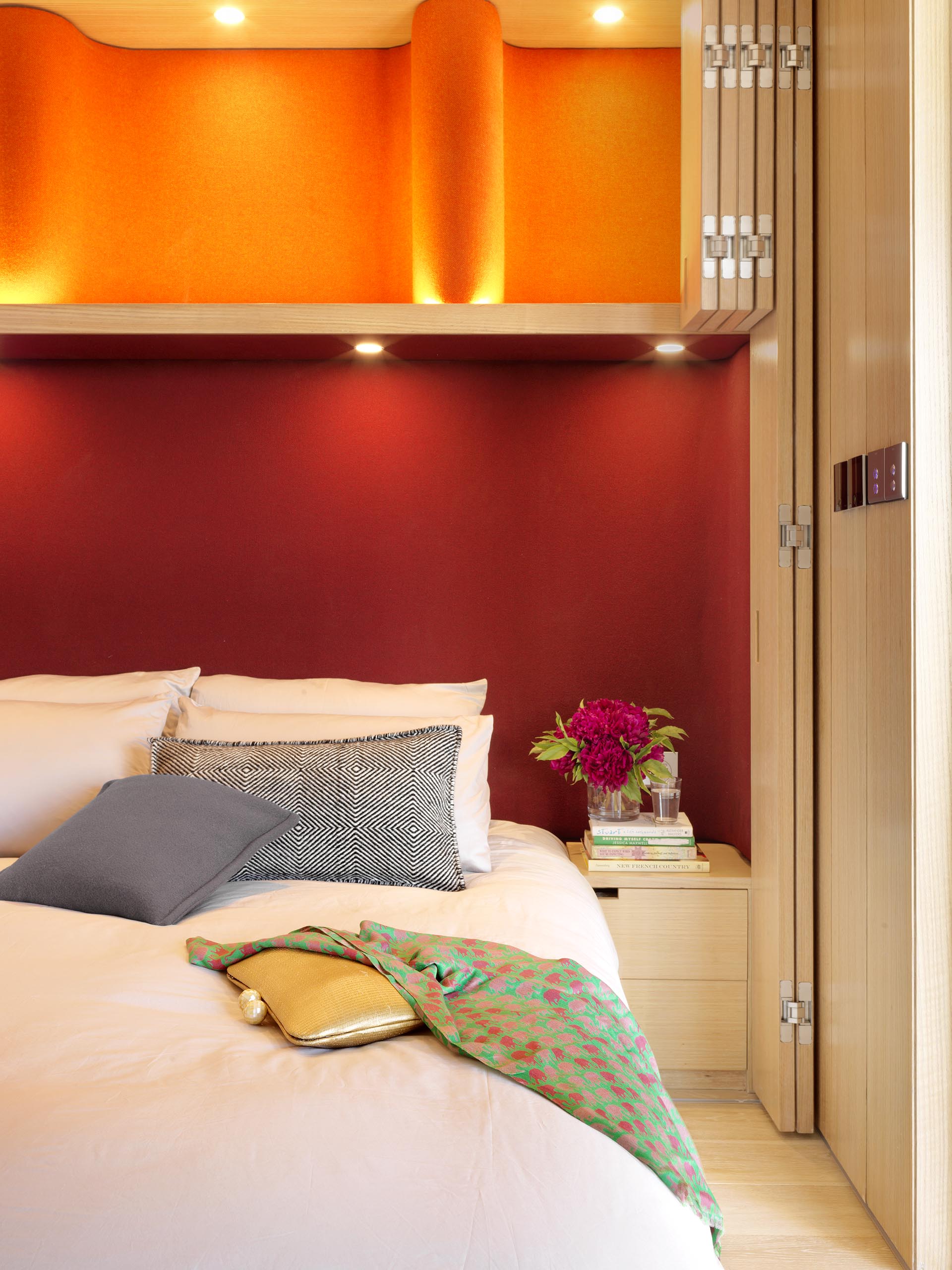 A dark red headboard sits below cabinets with an orange backdrop.