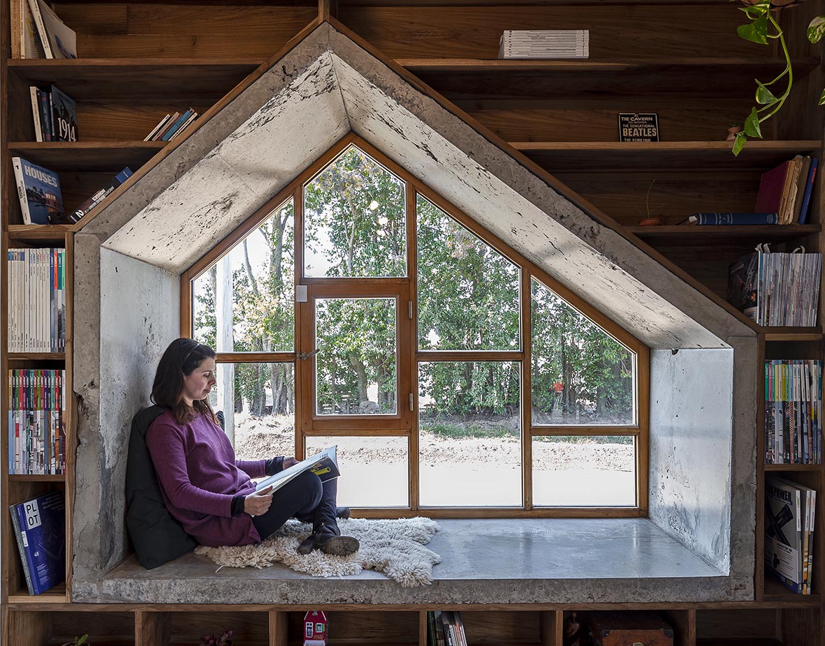 A concrete-lined window seat surrounded by bookshelves.