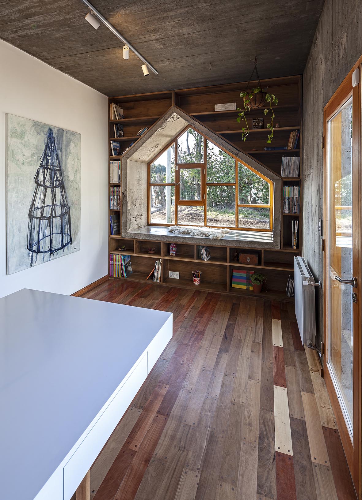 A concrete-lined window seat surrounded by shelving creates a reading nook.