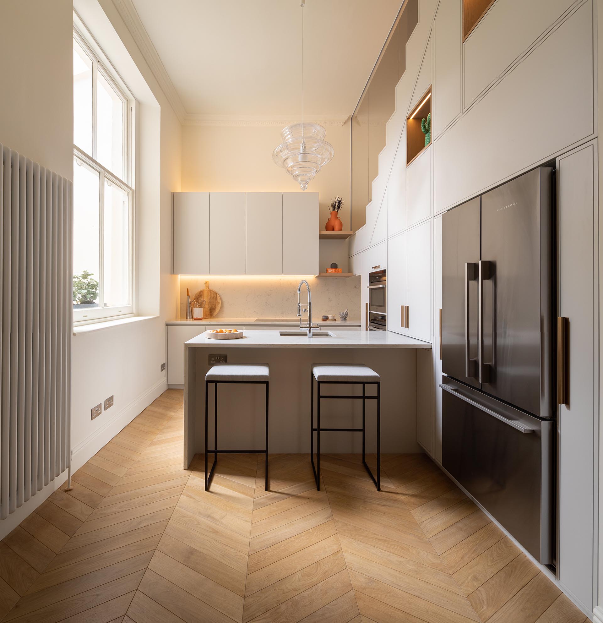 A modern white kitchen with white countertops, LED lighting, and plenty of storage.