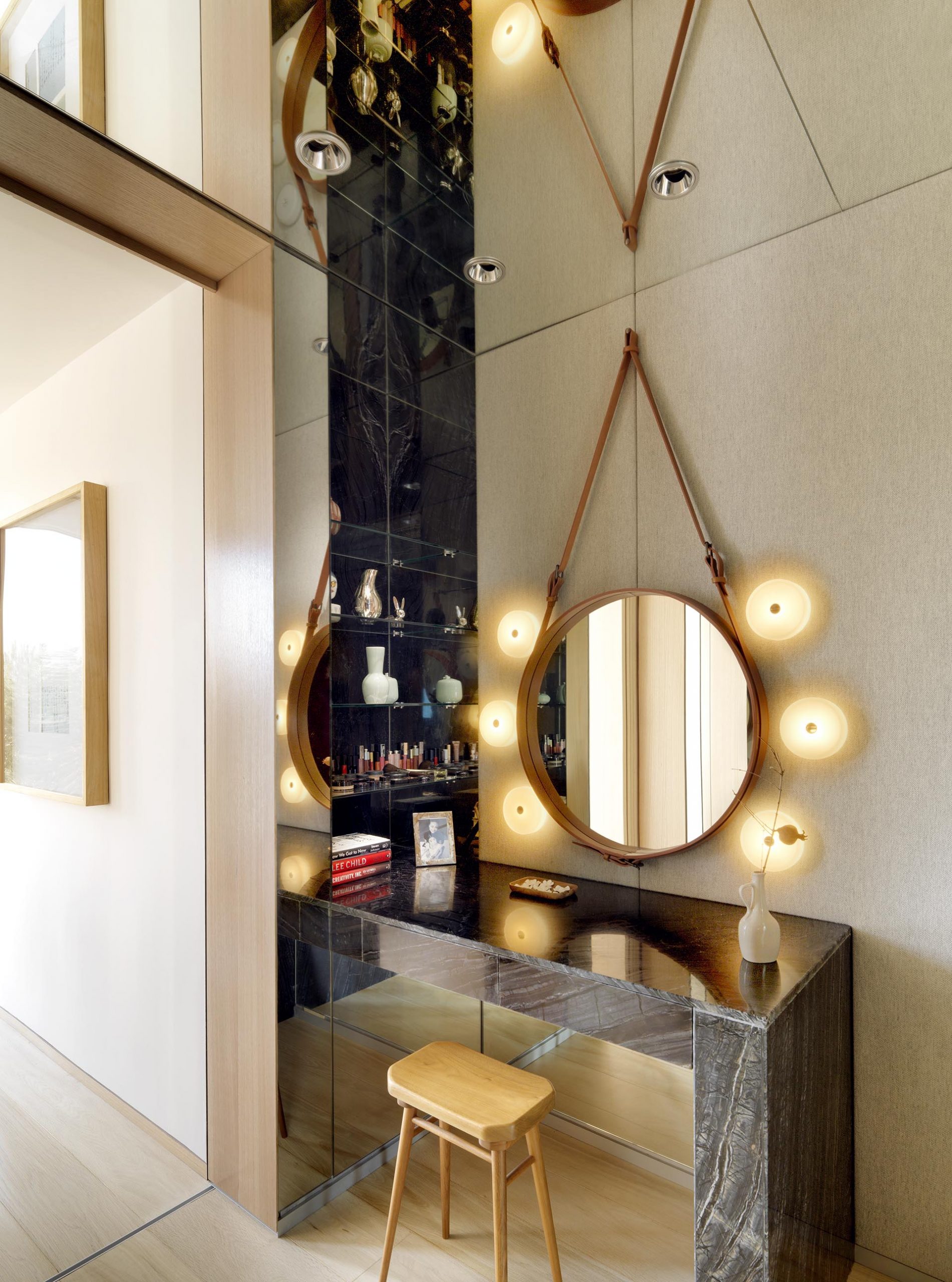 A makeup desk with a hanging round mirror.